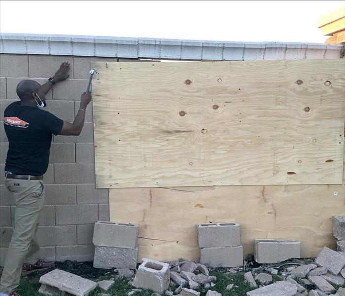 Man boarding up a damaged wall