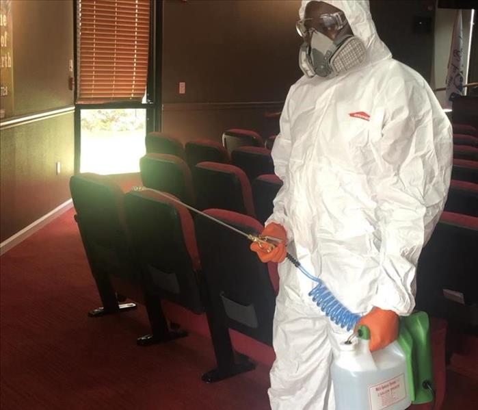 A Man in tyvek suit with an electric sprayer 